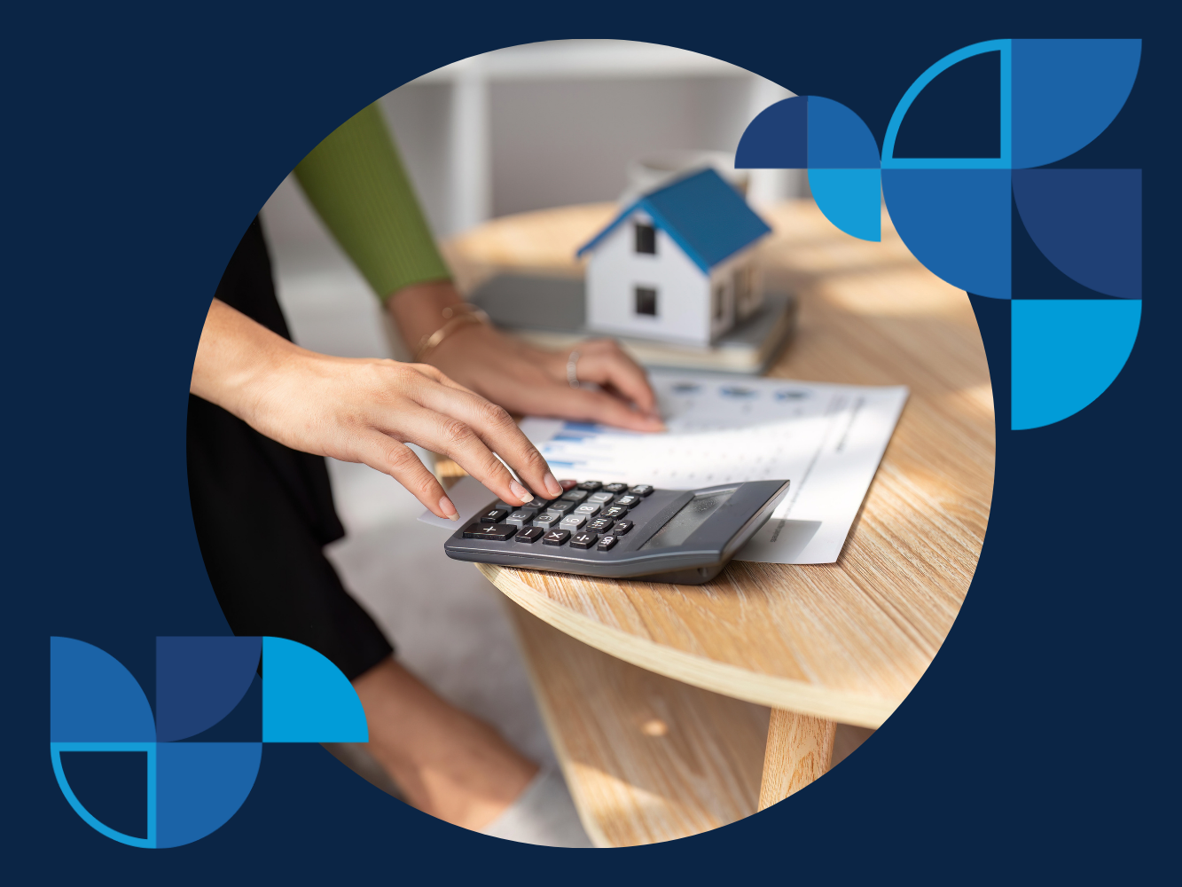 A person is using a calculator on a table. There is a pen next to the calculator and papers spread out on the table.